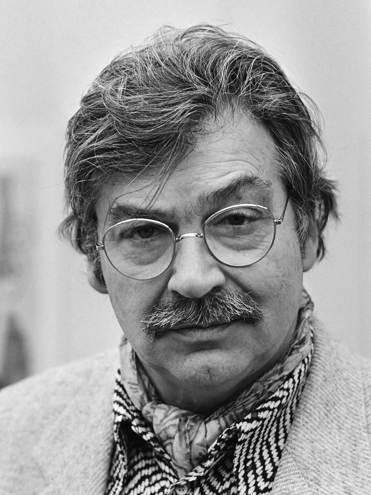 Karel Appel, medeoprichter van Cobra, geportretteerd met snor, ronde bril en sjaal